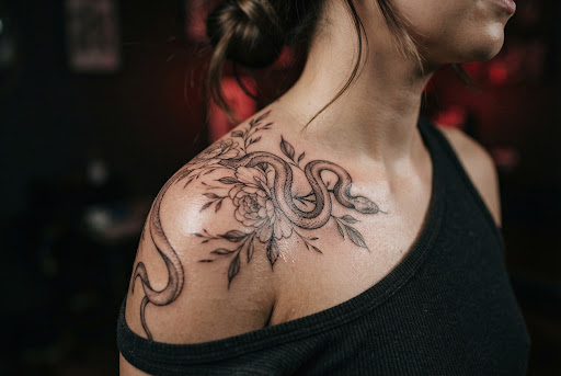 Detalle macro de máquina de tatuar profesional cargando pigmento negro y rojo en bandeja metálica esterilizada con guantes de nitrilo