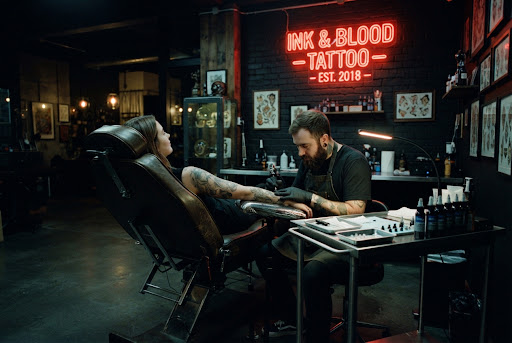 Interior del estudio de tatuajes Almamia en Berazategui con sillón ergonómico de cuero, lámparas cálidas, neón rojo y estación clínica de acero inoxidable